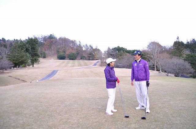 ゴルフ場にいる父親と母親に古希祝いの紫のウェアのプレゼント