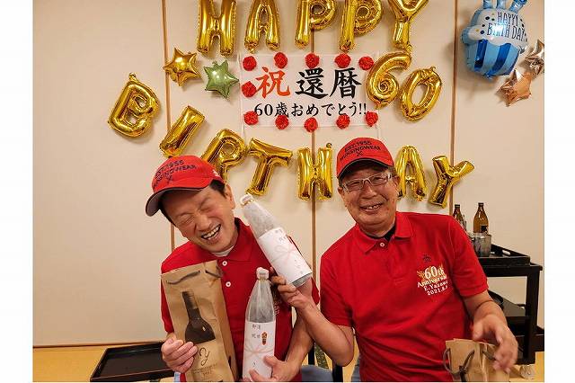 還暦祝いのポロシャツと帽子を着用している2人